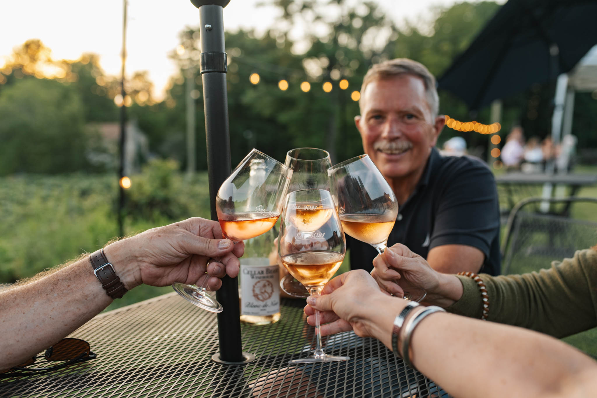 Cellar Beast Wine Club members toasting with glasses of rosé on the patio